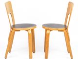 two wooden chairs with black leather seats on a white background