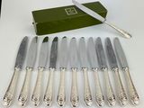 six silverplated knives and a box of knives on a table