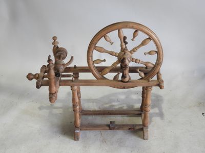un rouet posé sur un support en bois, sur fond blanc