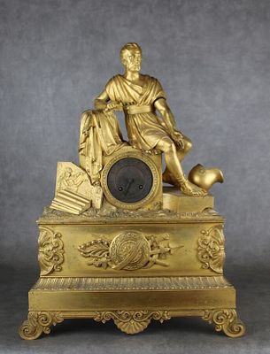 une horloge en or surmontée d'une statue représentant un homme tenant un ballon de football