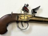 un vieux pistolet avec une poignée en bois sur une surface blanche