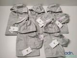 Quatre paires de vêtements pour bébé sont posées sur une table, avec leurs étiquettes encore attachées.