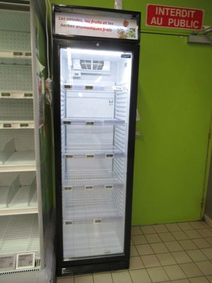 an empty refrigerator in the middle of a green wall