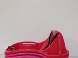 red and pink plastic shoe with black straps on a white surface