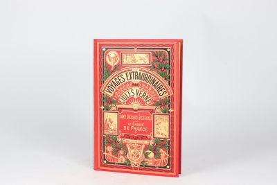 an old book with a red cover sitting on top of a white surface