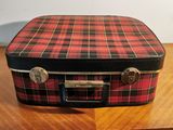 a red and black plaid suitcase sitting on a wooden table