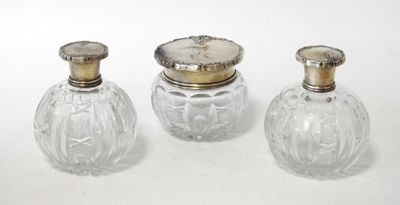 three glass bottles with silver lids sitting on top of a white surface