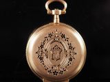 an antique gold pocket watch on a black surface with a black background