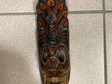 a wooden mask hanging on the wall on the floor
