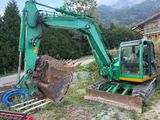 a green excavator that is sitting in the dirt