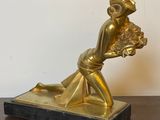 une statue représentant une femme tenant un panier de fleurs posé sur une table