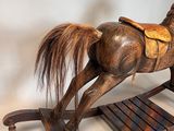 a wooden rocking horse with a saddle on it ' s back