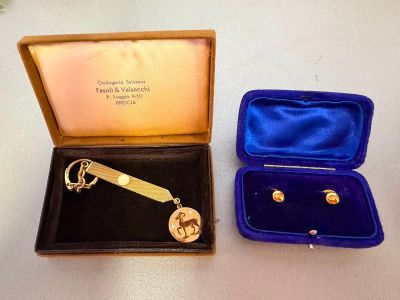 a gold keychain and a pair of earrings in a case