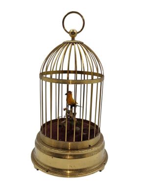 un oiseau doré dans une cage sur fond blanc