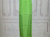 green dress on a mannequin stand in front of a white wall