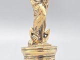 une statue en or représentant une femme tenant un enfant dans ses bras, posée sur un socle
