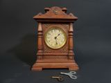 a small wooden clock with a key on a table