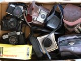 une boîte en carton remplie de vieux appareils photo et d'autres objets