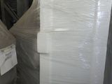 Des cartons contenant des matelas sont empilés sur des palettes dans un entrepôt