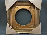 an old gold picture frame with a bow around it