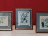 trois photos encadrées représentant un paysage de montagne, posées sur une table devant un mur rouge