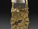 une horloge dorée entourée d'une chaîne, sur fond noir