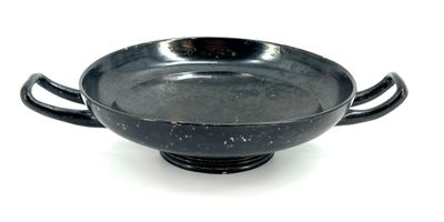 a black bowl with handles on a white surface