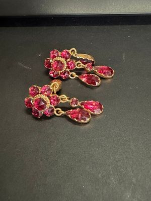 deux paires de boucles d'oreilles roses et dorées posées sur un fond noir