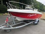 un bateau rouge et blanc sur une remorque dans un parking