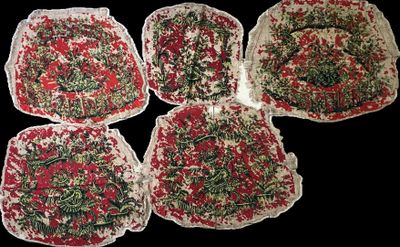 four pieces of cloth with red and green designs are on a black surface