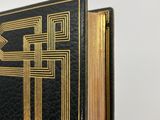 a close up of a black and gold book with gold trim