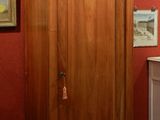 a tall wooden cabinet in a room with pictures on the wall