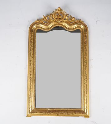 un miroir au cadre doré ouvragé accroché au mur au-dessus d'un lavabo