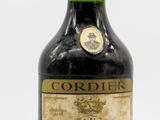 une vieille bouteille de Cordier est posée sur une surface blanche