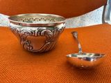 un bol en argent et une cuillère posés sur une chaise orange