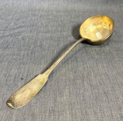 une cuillère ancienne ornée d'un smiley, posée sur une table