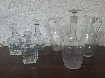 bottles and glasses on a table with a white wall in the background