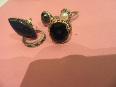 pair of rings with blue stones and pearls on a pink surface
