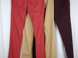 three pairs of pants hanging on a clothes rack in front of a white curtain