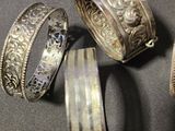 three different types of silver bracelets on a gray surface