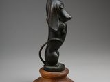 a bronze statue of a dog sitting on top of a wooden base