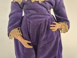 doll dressed in purple dress with gold lace collar and cuffs