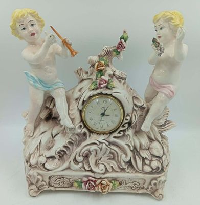 deux figurines posées sur une horloge, elle-même posée sur une table