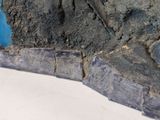 a large piece of stone on the ground next to a blue wall