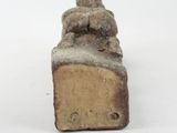 a small statue of a man sitting on top of a piece of wood