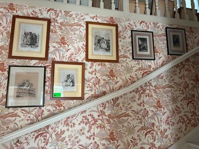 many pictures hanging on the wall above the stairs