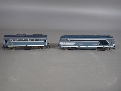 deux petits trains jouets posés côte à côte sur une surface grise
