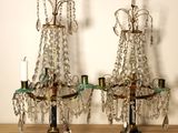 une paire de chandeliers anciens en laiton et cristal posés sur une table en bois