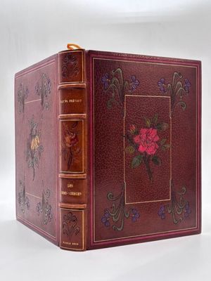 un vieux livre avec un motif de rose sur la couverture et une bordure dorée