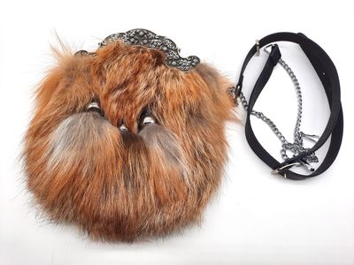 un sac à main en fourrure, entouré d'une chaîne, posé sur une surface blanche